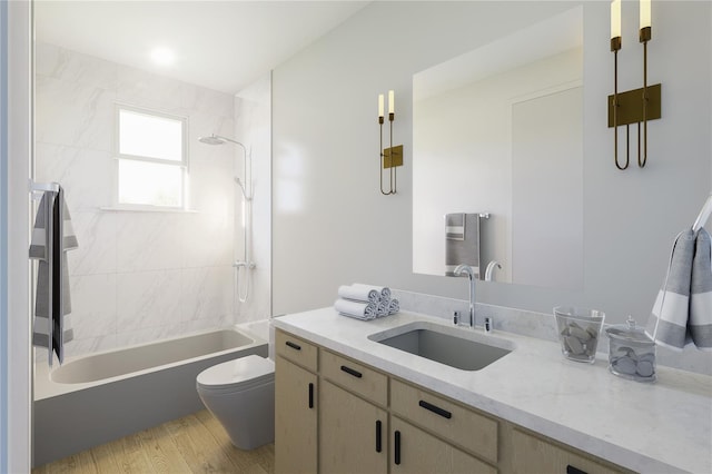 full bathroom featuring hardwood / wood-style floors, tiled shower / bath combo, vanity, and toilet