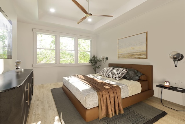 bedroom featuring light wood-type flooring, ceiling fan, and a raised ceiling