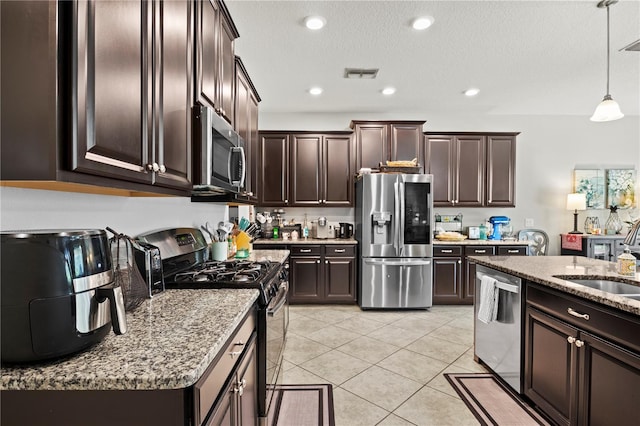 kitchen featuring dark brown cabinets, sink, hanging light fixtures, and appliances with stainless steel finishes