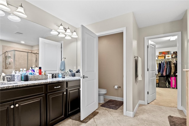 bathroom featuring tile patterned floors, vanity, toilet, and a shower with shower door