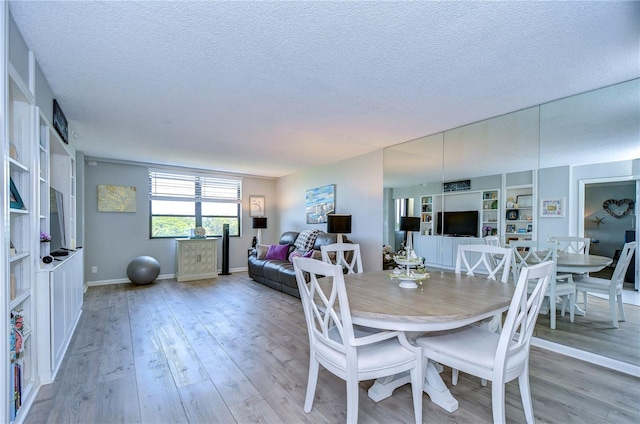 dining space with a textured ceiling and light wood-type flooring