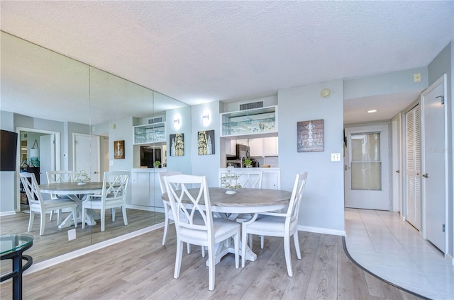 dining room featuring a textured ceiling and light hardwood / wood-style flooring