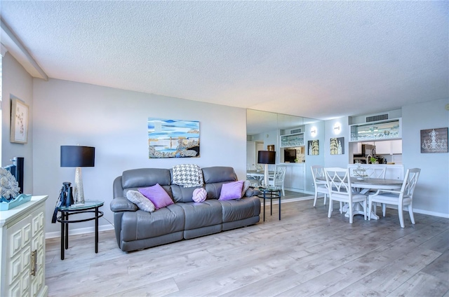 living room with a textured ceiling and light hardwood / wood-style flooring