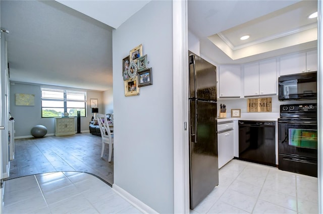 kitchen with white cabinetry, crown molding, light hardwood / wood-style floors, a tray ceiling, and black appliances