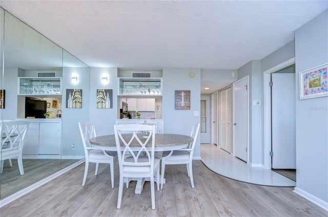 dining room featuring light hardwood / wood-style floors and a textured ceiling