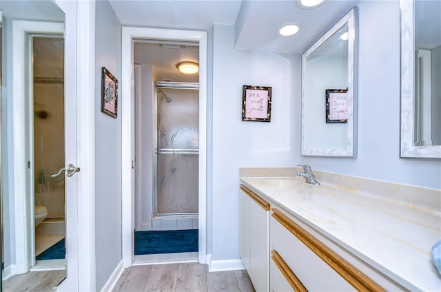 bathroom featuring wood-type flooring, vanity, toilet, and walk in shower