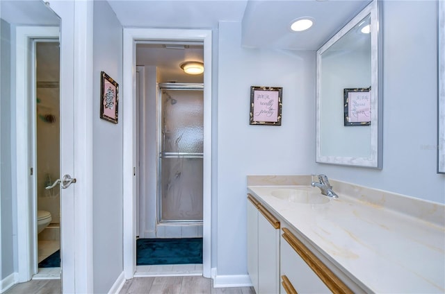 bathroom featuring hardwood / wood-style floors, toilet, an enclosed shower, and vanity