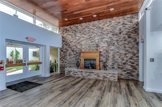 unfurnished living room featuring a towering ceiling, plenty of natural light, and wooden ceiling