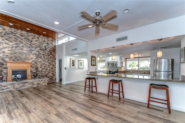 kitchen featuring a kitchen bar, appliances with stainless steel finishes, kitchen peninsula, decorative light fixtures, and white cabinets