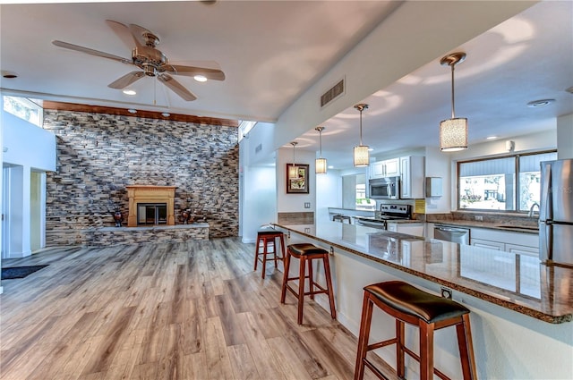 kitchen featuring white cabinets, appliances with stainless steel finishes, kitchen peninsula, and a kitchen breakfast bar