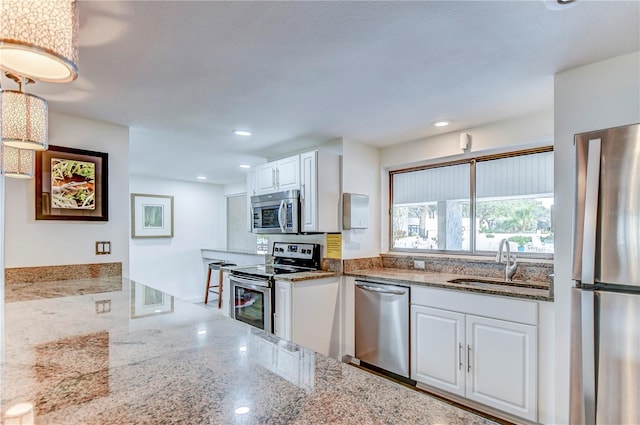 kitchen featuring white cabinetry, sink, light stone countertops, and appliances with stainless steel finishes