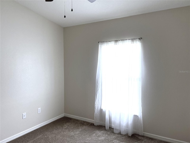 carpeted empty room featuring ceiling fan and baseboards