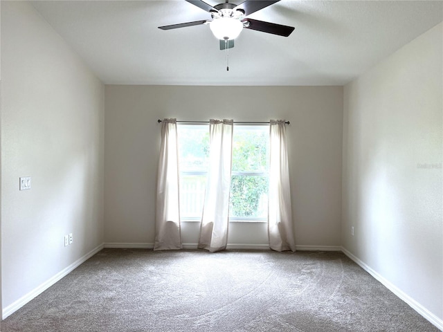 carpeted spare room featuring ceiling fan and baseboards