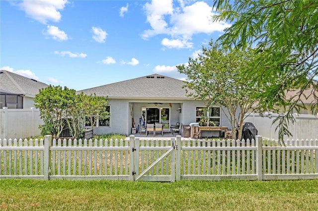 back of property with stucco siding, a gate, fence private yard, roof with shingles, and ceiling fan