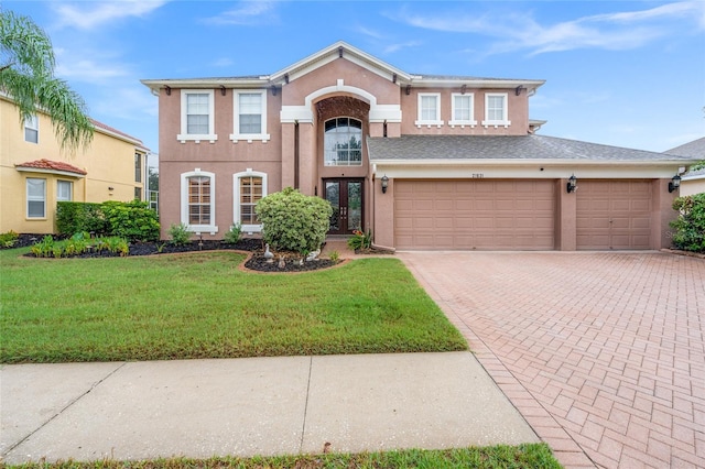 view of front of property featuring french doors, a garage, and a front lawn