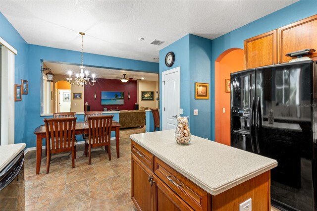 kitchen featuring a textured ceiling, a kitchen island, black appliances, and decorative light fixtures