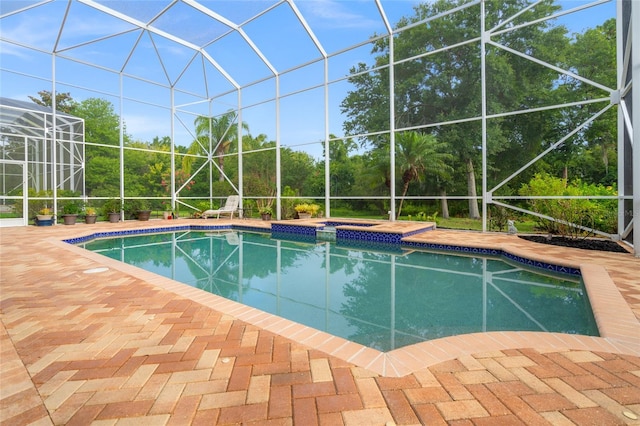 view of swimming pool with glass enclosure, an in ground hot tub, and a patio area