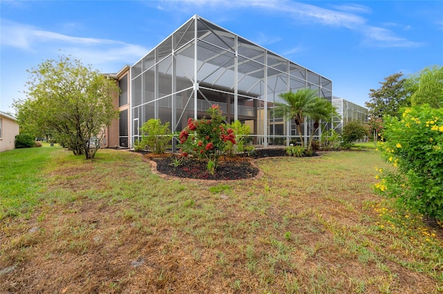 rear view of property featuring a lawn and glass enclosure