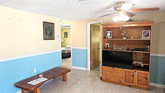 living room with ceiling fan and a textured ceiling