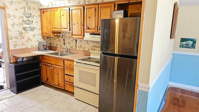 kitchen with a textured ceiling, white range with electric stovetop, sink, stainless steel refrigerator, and light tile patterned flooring