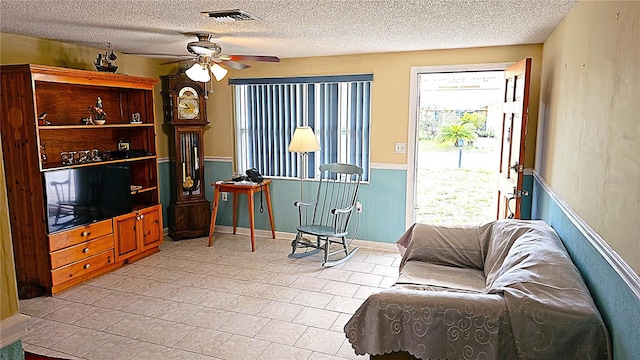 living room with ceiling fan and a textured ceiling