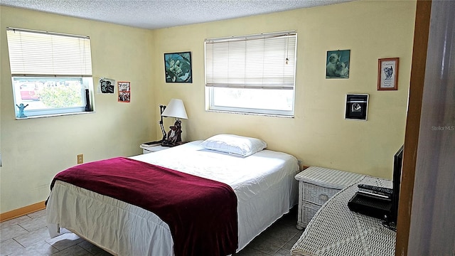 tiled bedroom featuring a textured ceiling and multiple windows