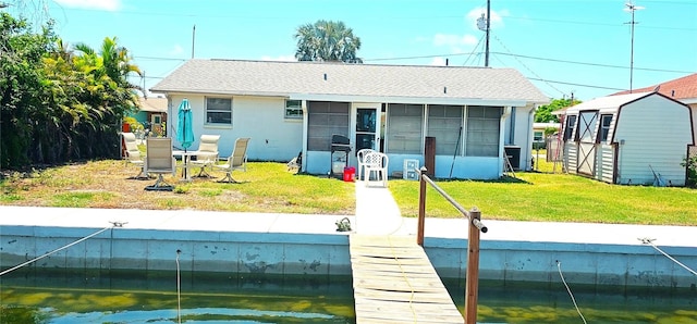 rear view of property with a storage shed, a yard, and a sunroom