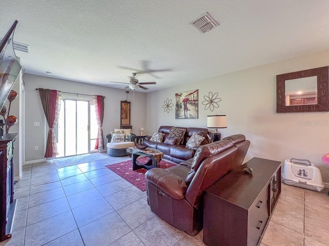 living room featuring ceiling fan, light tile patterned flooring, and a textured ceiling