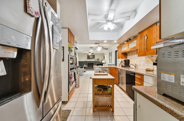 kitchen with backsplash, ceiling fan, light tile patterned floors, a tray ceiling, and stainless steel appliances