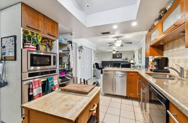 kitchen with ceiling fan, sink, stainless steel appliances, light tile patterned floors, and ornamental molding