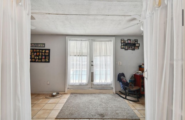 doorway with light tile patterned floors, a textured ceiling, french doors, and ceiling fan