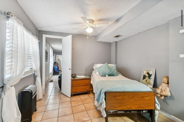 bedroom with ceiling fan, light tile patterned flooring, and a textured ceiling