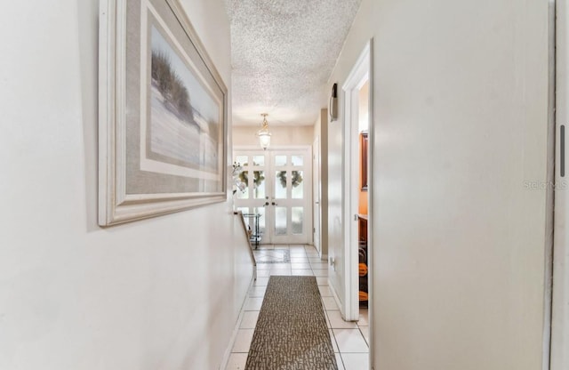 corridor featuring french doors, light tile patterned flooring, and a textured ceiling