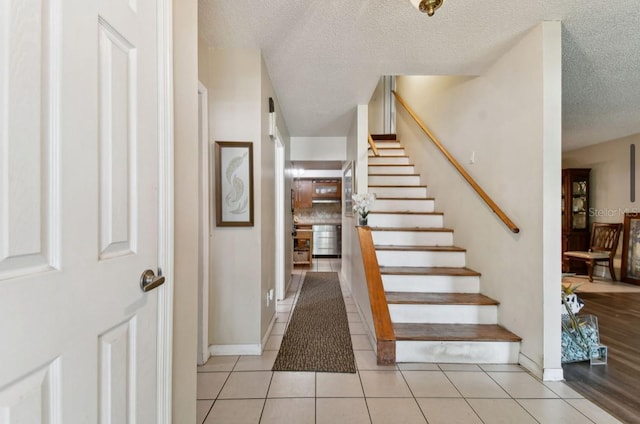 staircase featuring tile patterned flooring and a textured ceiling