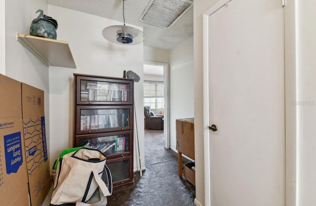 hall featuring dark carpet and a textured ceiling