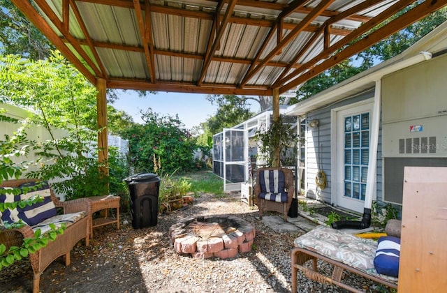 view of patio with a sunroom and an outdoor fire pit