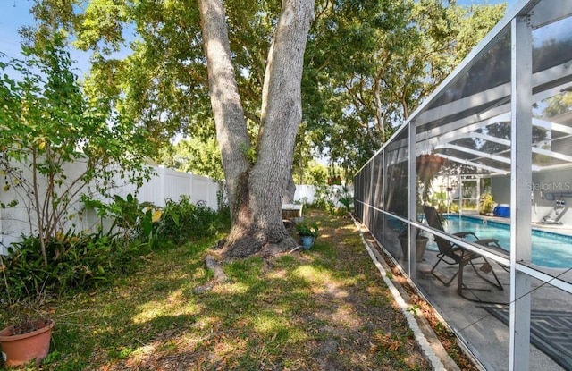 view of yard featuring a fenced in pool and glass enclosure