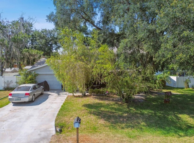 view of property hidden behind natural elements with a garage and a front lawn