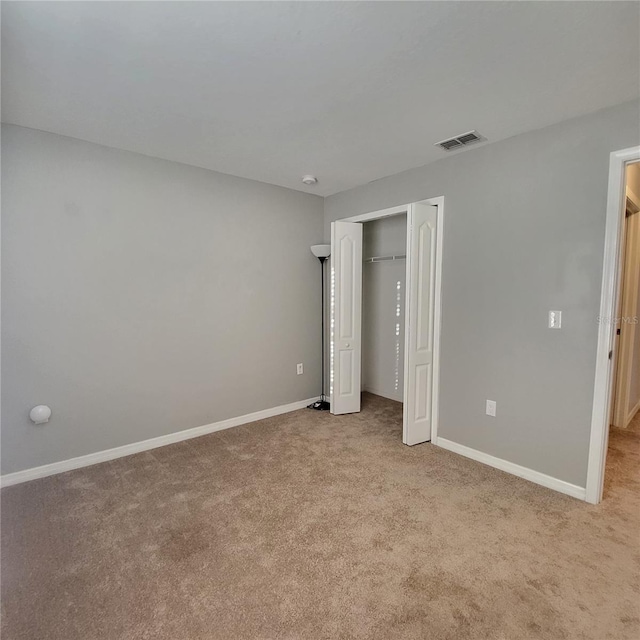 unfurnished bedroom with light colored carpet and a closet