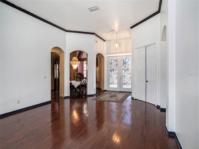 foyer with a notable chandelier, dark hardwood / wood-style flooring, ornamental molding, and french doors