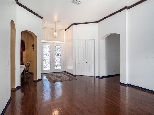 entrance foyer featuring an inviting chandelier, crown molding, dark wood-type flooring, and french doors