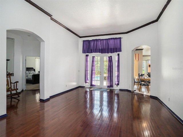 empty room featuring a textured ceiling, crown molding, french doors, and dark hardwood / wood-style floors