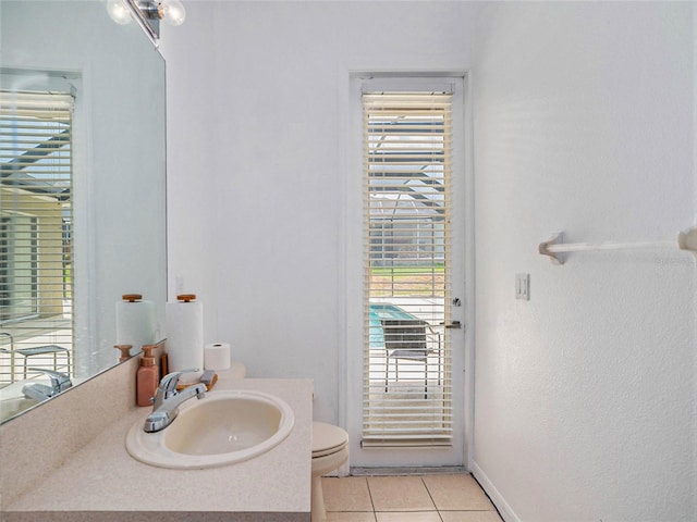 bathroom with toilet, vanity, and tile patterned floors