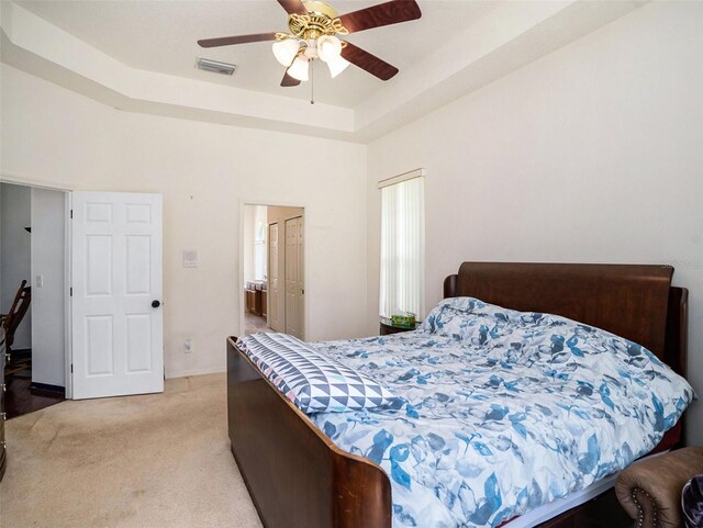 carpeted bedroom featuring ceiling fan and a tray ceiling