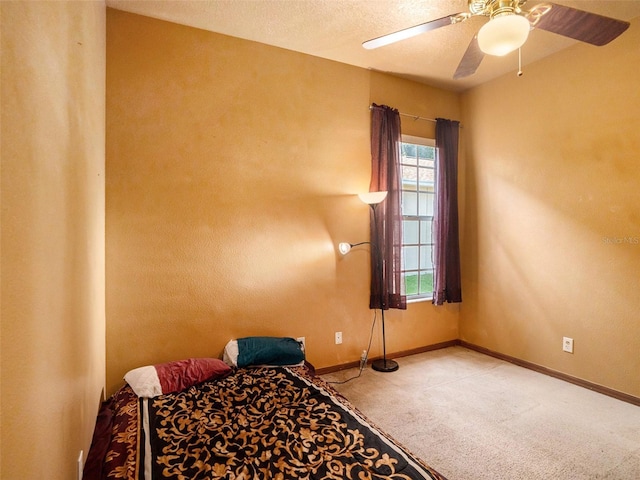 bedroom with ceiling fan, light carpet, and a textured ceiling