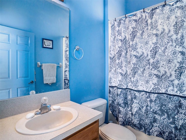 bathroom with curtained shower, vanity, and toilet