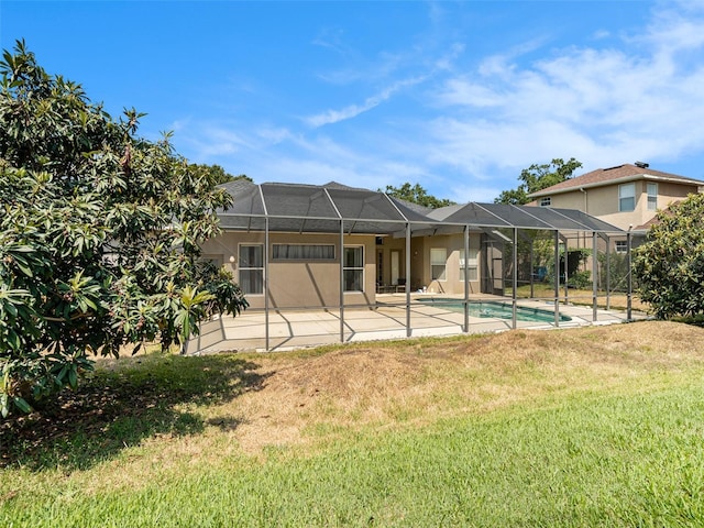 rear view of property featuring a yard, glass enclosure, and a patio area