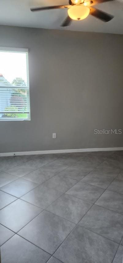 tiled spare room with a ceiling fan and baseboards