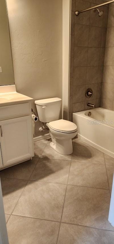 full bathroom featuring tile patterned flooring, vanity, tiled shower / bath, and toilet