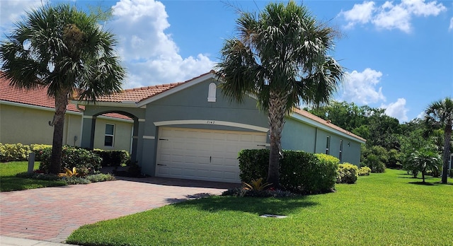 view of front of house with a garage, a front yard, decorative driveway, and stucco siding